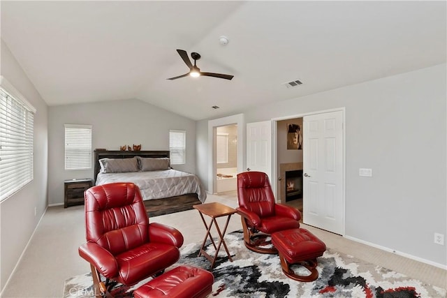 bedroom featuring light carpet, connected bathroom, vaulted ceiling, and ceiling fan