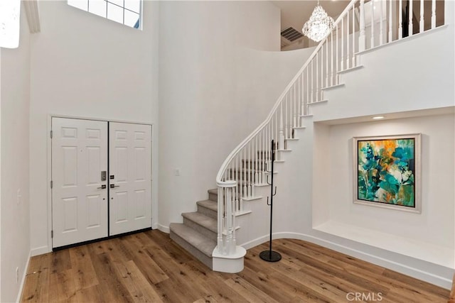 entrance foyer with hardwood / wood-style flooring and a towering ceiling