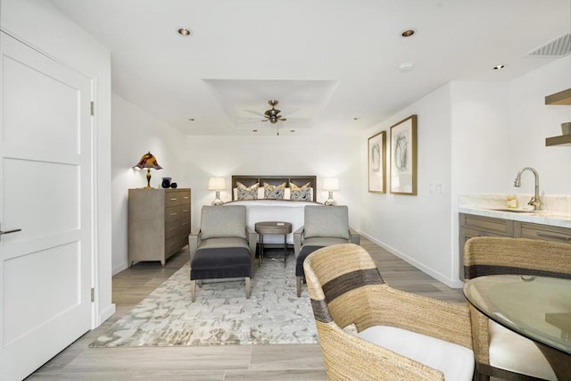 bedroom featuring ceiling fan, sink, and light wood-type flooring