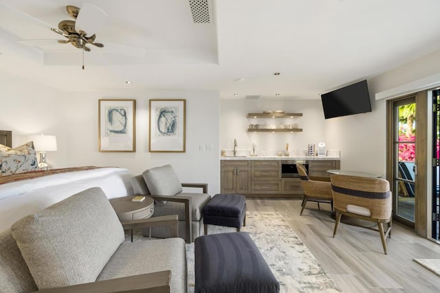 bedroom with connected bathroom, ceiling fan, light hardwood / wood-style flooring, and indoor wet bar