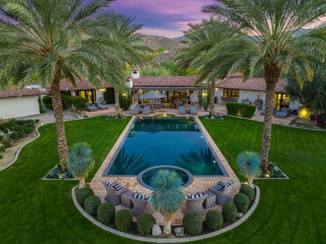 pool at dusk with a lawn, a patio, and an outdoor bar