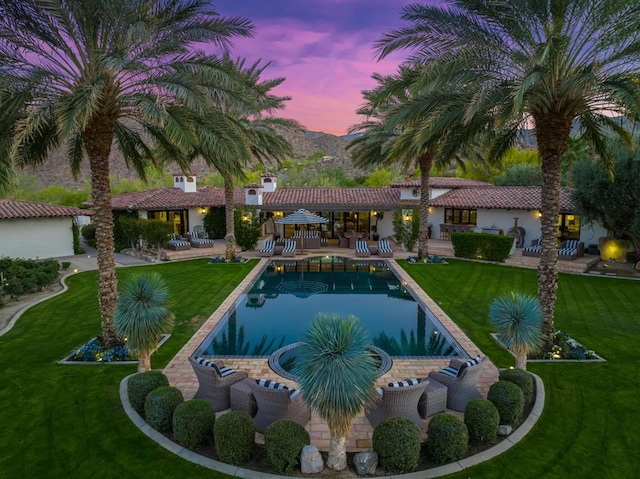 pool at dusk with a patio area