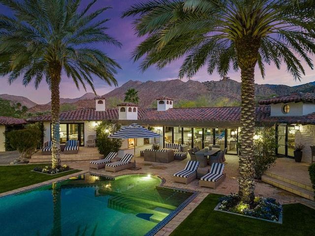 pool at dusk with a mountain view, an outdoor hangout area, and a patio