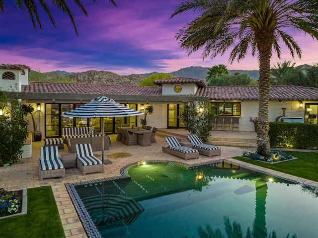 back house at dusk featuring a mountain view, a patio, and an outdoor hangout area