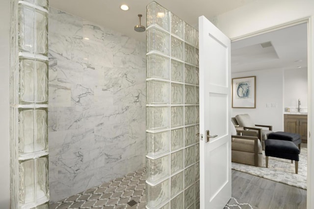 bathroom with hardwood / wood-style floors, vanity, and tiled shower