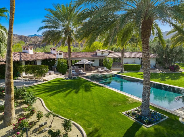 view of swimming pool featuring a mountain view, a patio area, and a lawn