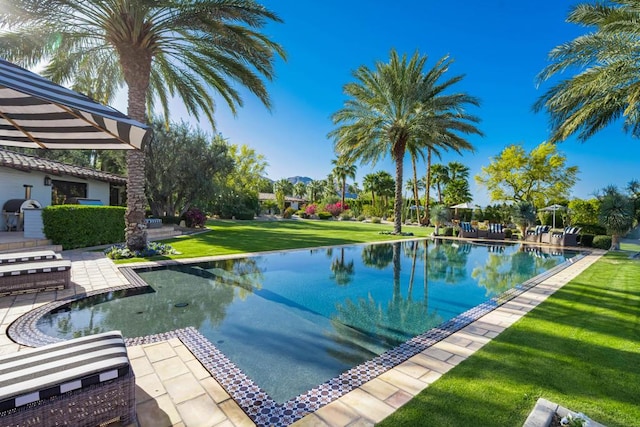 view of swimming pool featuring a lawn, a patio area, and a water view