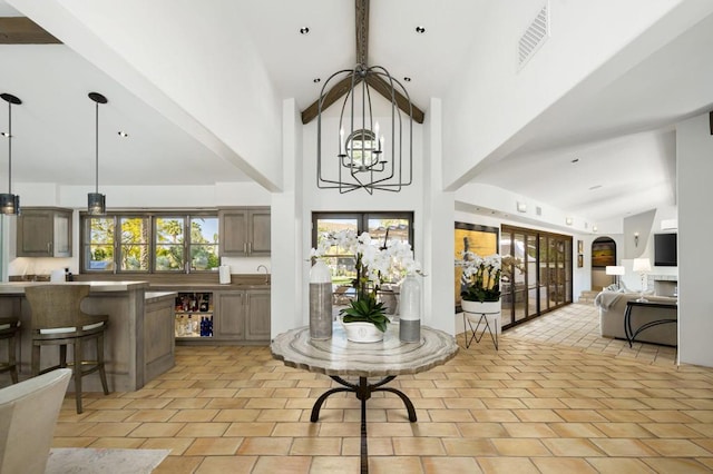 foyer entrance with beam ceiling, sink, high vaulted ceiling, a chandelier, and light tile patterned floors