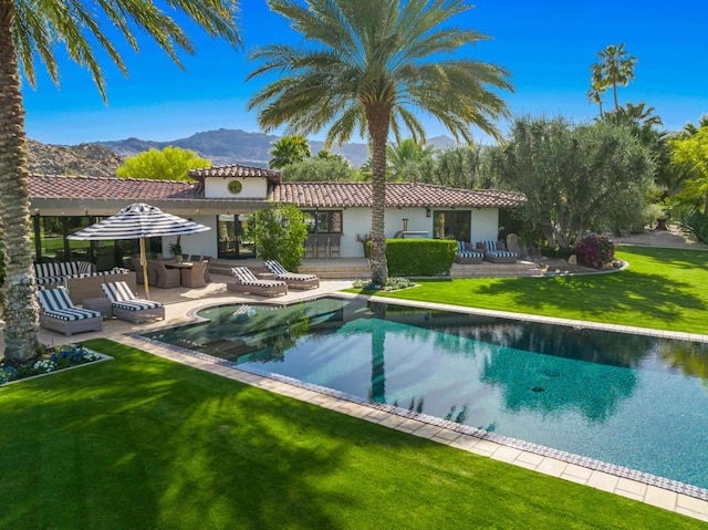 back of house featuring a lawn, a patio area, and a mountain view