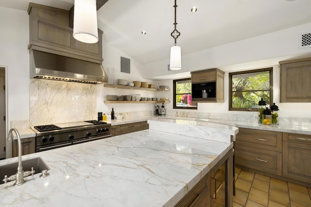 kitchen with exhaust hood, hanging light fixtures, sink, vaulted ceiling, and stainless steel range