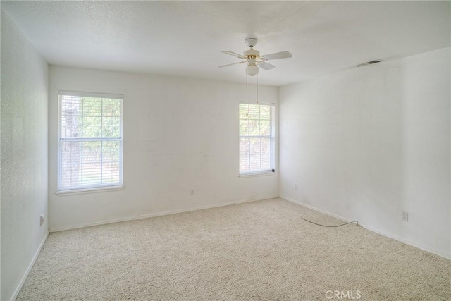 carpeted spare room featuring a wealth of natural light and ceiling fan