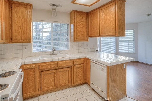 kitchen featuring kitchen peninsula, tile countertops, white appliances, and sink