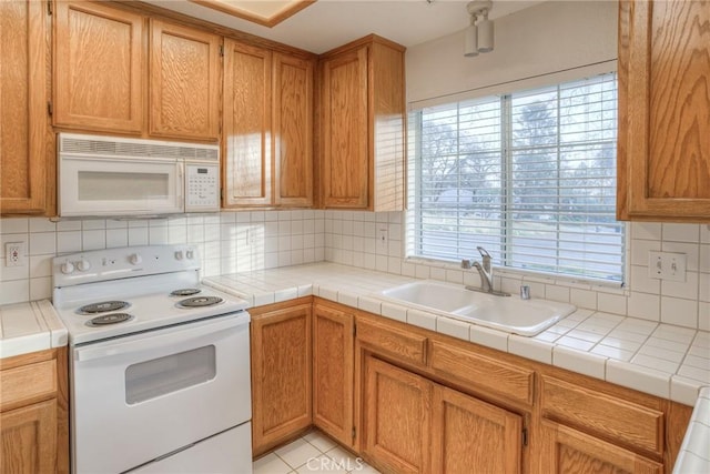 kitchen with tile countertops, backsplash, white appliances, and sink