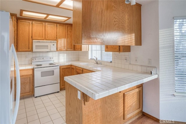 kitchen featuring sink, tasteful backsplash, kitchen peninsula, tile countertops, and white appliances