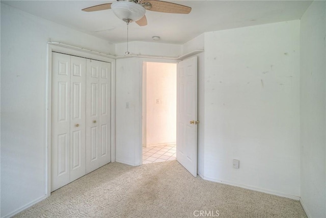 unfurnished bedroom featuring light carpet, a closet, and ceiling fan