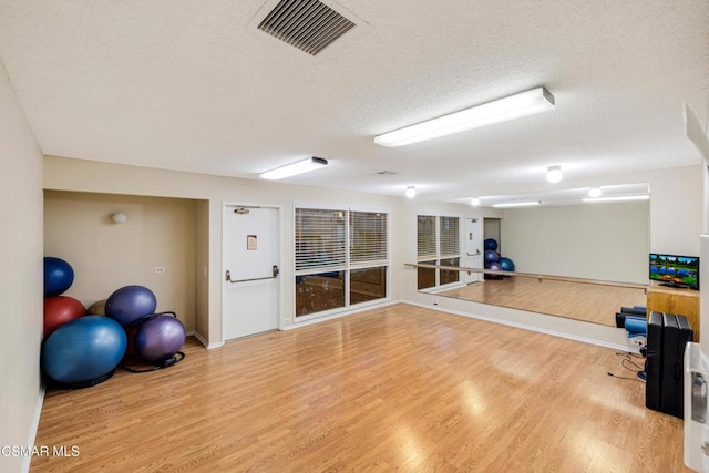 workout room with wood-type flooring and a textured ceiling