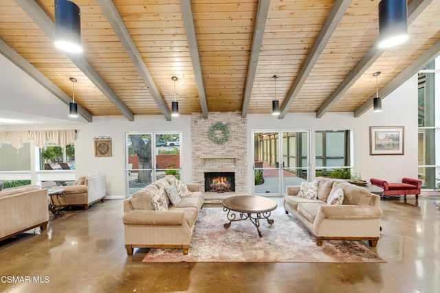 living room with vaulted ceiling with beams, a stone fireplace, wood ceiling, and concrete flooring