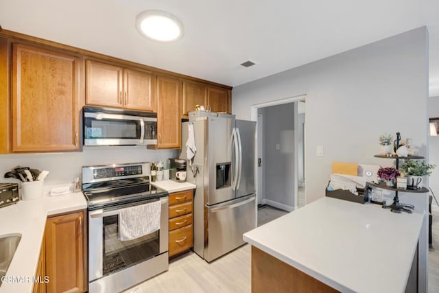 kitchen featuring appliances with stainless steel finishes and light hardwood / wood-style flooring