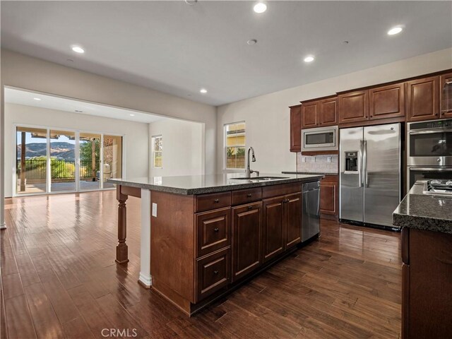 kitchen featuring stainless steel appliances, an island with sink, sink, and dark hardwood / wood-style floors