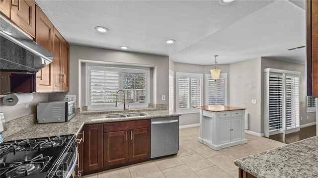 kitchen with sink, stainless steel appliances, a textured ceiling, decorative light fixtures, and a kitchen island