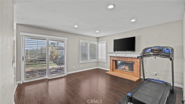 workout room with a fireplace, a textured ceiling, and dark wood-type flooring