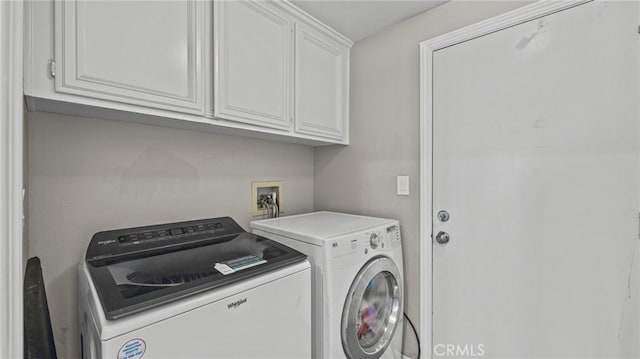 laundry room featuring washing machine and clothes dryer and cabinets