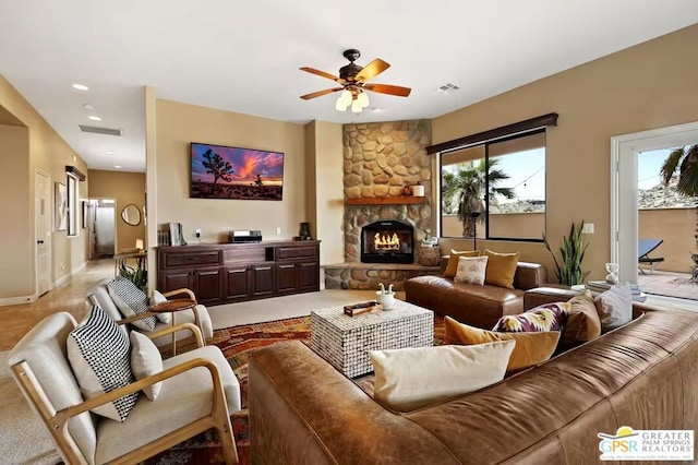 living room featuring ceiling fan and a stone fireplace