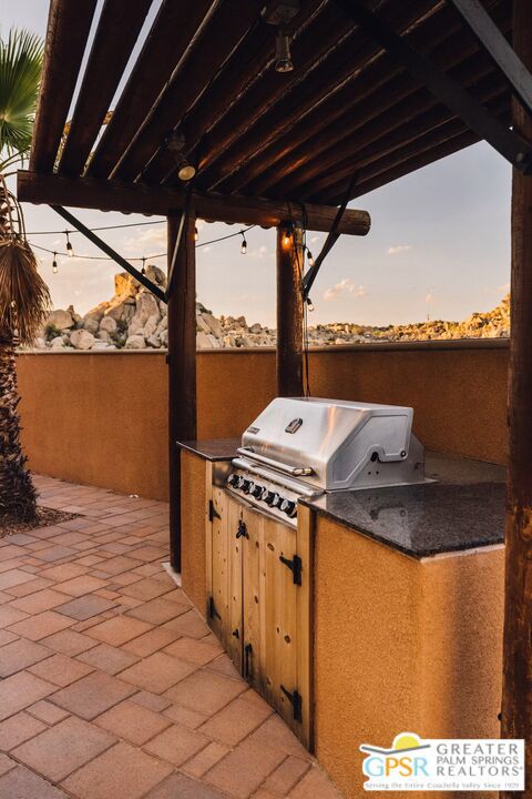 patio terrace at dusk featuring grilling area and exterior kitchen