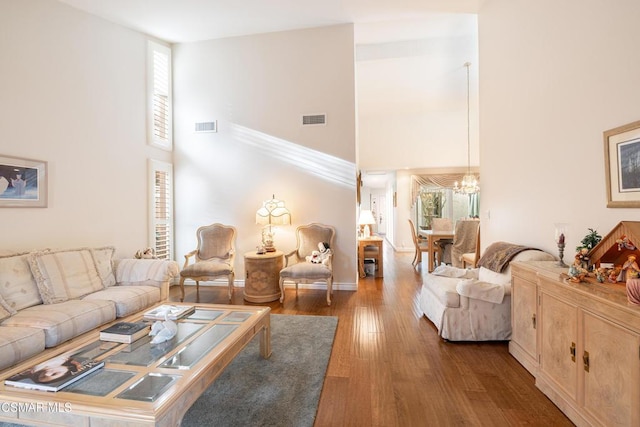 living room featuring a towering ceiling, a chandelier, and hardwood / wood-style flooring