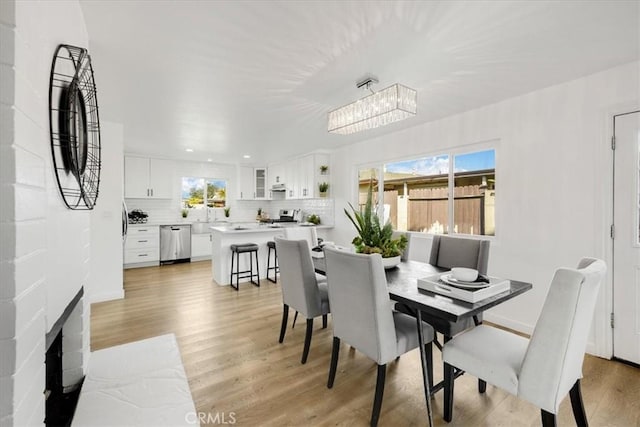 dining area featuring a fireplace, light wood-type flooring, and a notable chandelier