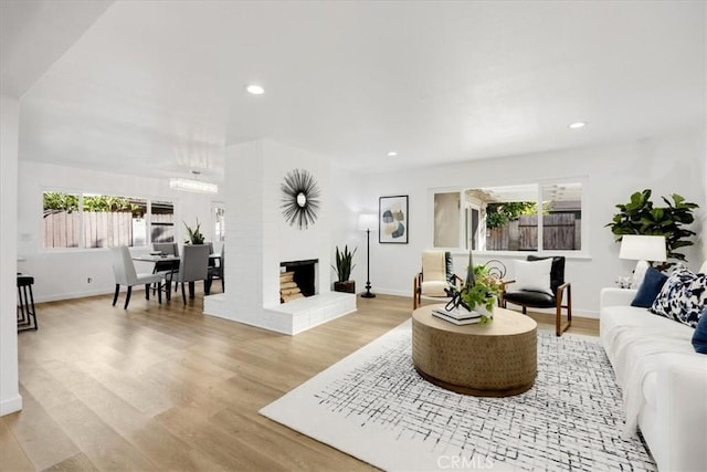 living room with plenty of natural light, light hardwood / wood-style floors, and a brick fireplace