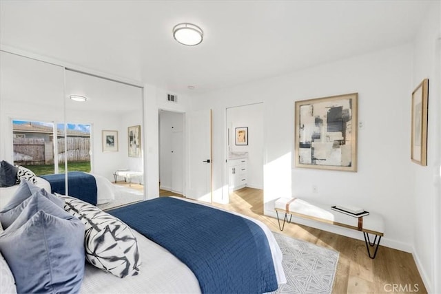 bedroom featuring ensuite bath, light hardwood / wood-style floors, access to exterior, and a closet