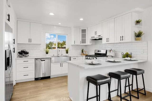 kitchen with white cabinets, stainless steel appliances, kitchen peninsula, and sink