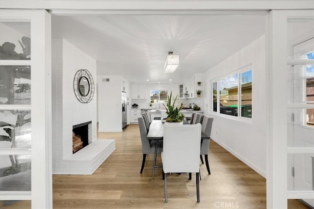 dining space featuring a fireplace and light wood-type flooring