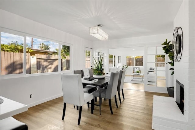 dining space with light hardwood / wood-style floors and a brick fireplace