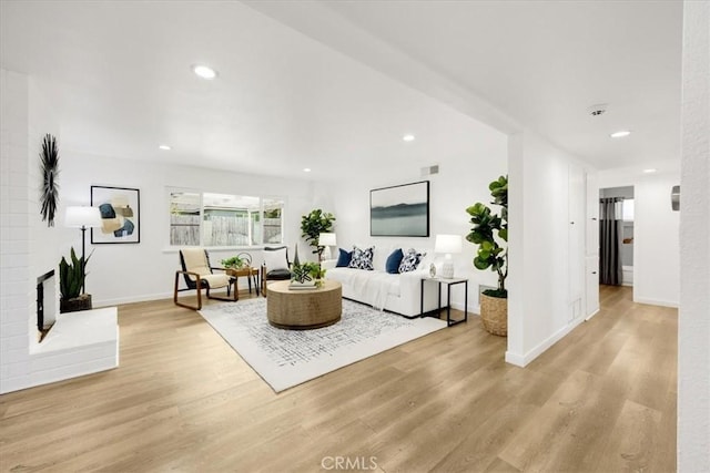 living room with light hardwood / wood-style floors and a brick fireplace