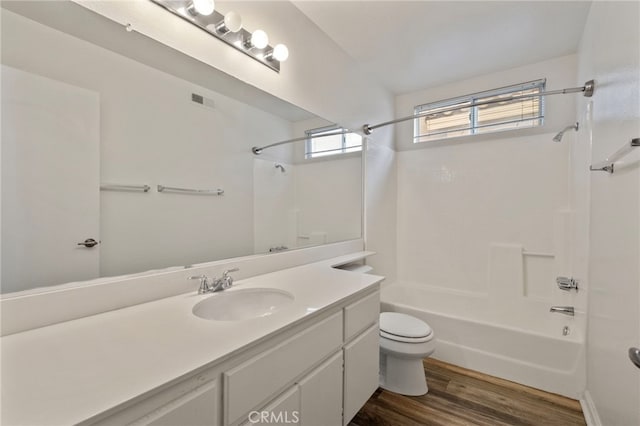 full bathroom featuring hardwood / wood-style floors, vanity, toilet, and  shower combination