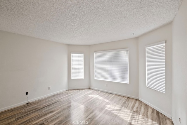 empty room featuring wood-type flooring and a textured ceiling