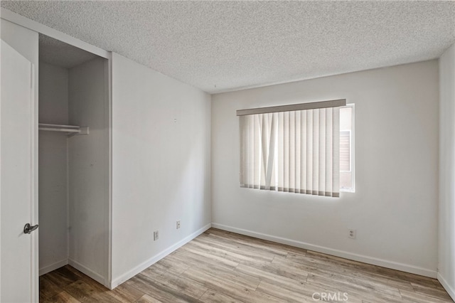 unfurnished bedroom with a closet, a textured ceiling, and light wood-type flooring