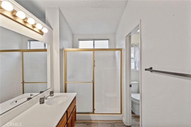 bathroom featuring a textured ceiling, vaulted ceiling, toilet, vanity, and hardwood / wood-style flooring