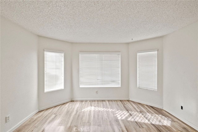 empty room featuring light wood-type flooring and a textured ceiling