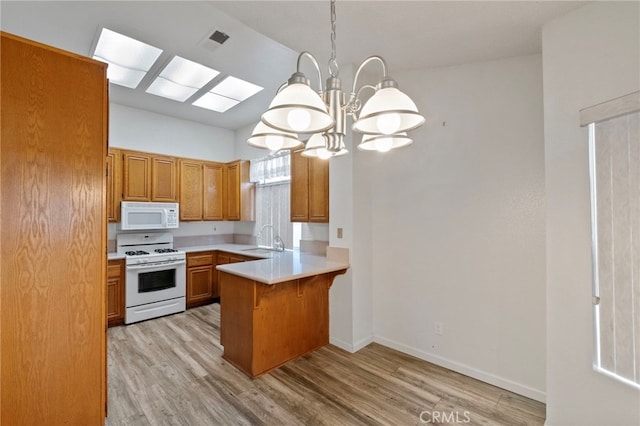 kitchen featuring sink, hanging light fixtures, kitchen peninsula, white appliances, and light wood-type flooring