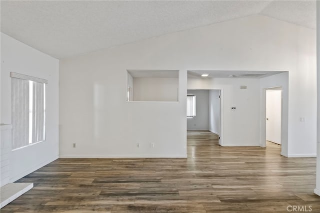 spare room with a textured ceiling, dark hardwood / wood-style flooring, and lofted ceiling