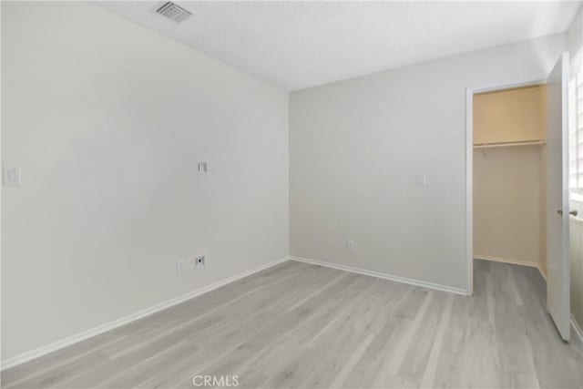 unfurnished bedroom with a closet, light hardwood / wood-style floors, and a spacious closet