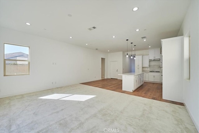 kitchen featuring decorative backsplash, pendant lighting, white cabinets, light hardwood / wood-style floors, and a kitchen island