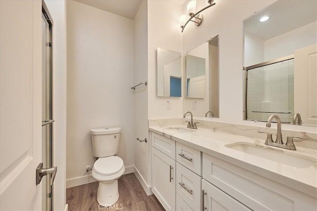 bathroom featuring a shower with door, vanity, wood-type flooring, and toilet