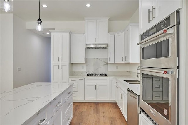 kitchen featuring white cabinets, pendant lighting, light hardwood / wood-style floors, and stainless steel appliances