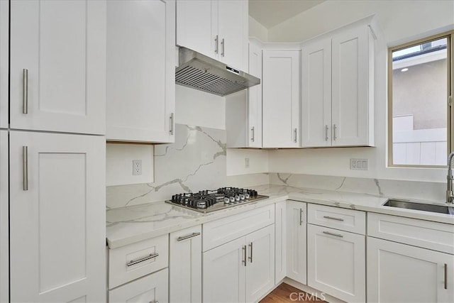 kitchen with light stone countertops, white cabinetry, stainless steel gas cooktop, and sink