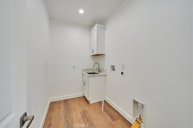 clothes washing area with hookup for an electric dryer, washer hookup, light wood-type flooring, cabinets, and sink