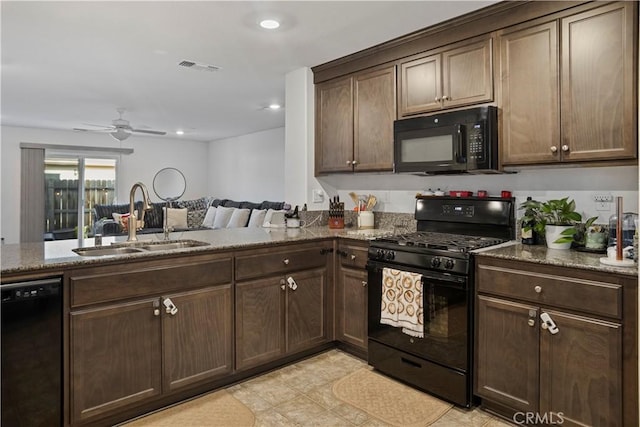 kitchen with sink, dark stone countertops, dark brown cabinetry, and black appliances